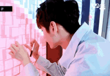 a man is writing on a wall with a pen and a mnet logo in the background