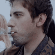 a man with a cigarette in his mouth looks to the side