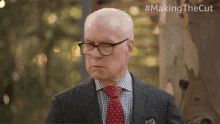 a man in a suit and tie is standing in front of a tree with the hashtag #makingthecut on the bottom