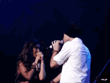 a woman singing into a microphone while a man wipes his eyes