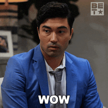 a man in a blue suit and tie has the word wow on his chest