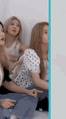 a group of women are sitting on the floor and one of them is pointing at the camera .