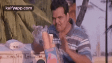 a man in a striped shirt is holding a bottle of water in his hand .