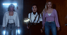 three women standing next to each other in a dark room holding a magnifying glass