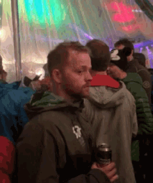 a man wearing a jacket with the letter g on it is holding a can of beer