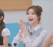 a girl in a white shirt and gray vest is smiling
