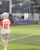 a boy wearing a white shirt with the number 10 on the back is running on a soccer field