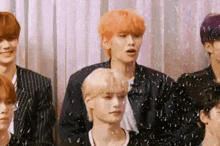 a group of young men standing next to each other in front of a curtain .