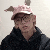 a person wearing glasses and a pink hat with ears