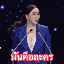 a woman in a blue suit stands in front of a microphone with a foreign language written in red