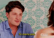 a man in a blue shirt is talking to a woman and says to marry you