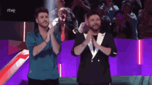 two men applauding in front of a crowd with rtve written on the screen