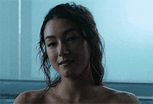 a woman without a shirt is taking a bath in a bathtub and smiling .