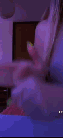 a blurry picture of a woman laying on a bed with a tv in the background