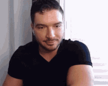 a man in a black shirt is sitting in front of a window