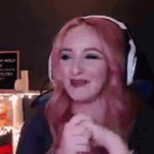 a woman with red hair is wearing headphones and smiling while sitting in a chair .