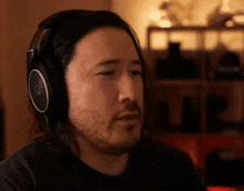 a man with long hair and a beard wearing headphones with the letter v on them .