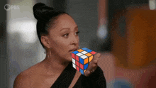 a woman holding a rubik 's cube in front of her mouth
