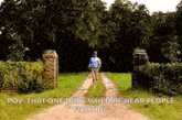 a man is walking down a dirt road in a field with trees in the background .