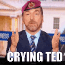 a man in a suit and tie is crying and wearing a purple beret .