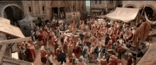 a large group of people are gathered around a fountain in a medieval town square .