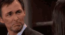 a man in a suit is making a funny face in front of a woman .