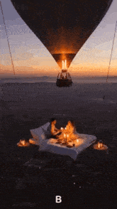 a hot air balloon is flying over a bed with two people sitting on it .