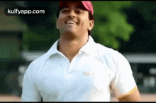 a man in a white polo shirt and a red hat is smiling .