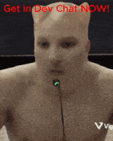 a shirtless man speaking into a microphone with the words " get in dev chat now " behind him