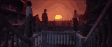 a couple standing on a balcony watching the sun set