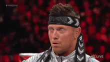 a wrestler is wearing a headband with arrows on it during a live broadcast