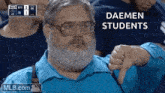a man with glasses and a beard gives a thumbs down sign