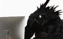 a monster is sitting in front of a computer monitor .