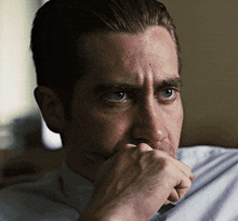 a close up of a man 's face with his hand covering his mouth