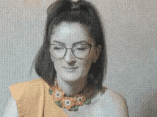 a woman wearing glasses and a necklace with flowers on it is smiling .
