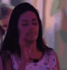a woman in a purple dress is making a face with her eyes closed .