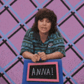 a woman wearing a nike shirt is sitting at a table with a sign that says anna