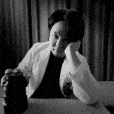 a black and white photo of a woman sitting at a table