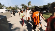 a group of children are dancing in a park and one of them is wearing an orange shirt that says sports camp