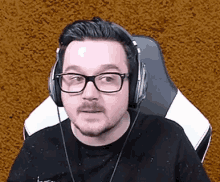 a man wearing glasses and headphones is sitting in a chair and making a funny face .