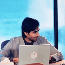 a man is sitting at a desk with a laptop with a sticker on it that says nk