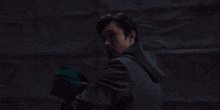 a man in a dark room holds a green blanket