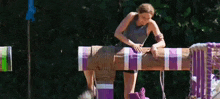 a woman is standing on a wooden post with purple stripes .