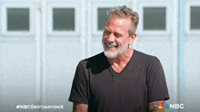 a man with a beard is smiling in front of a nbc sign