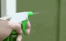 a person is holding a spray bottle in their hand and spraying it .