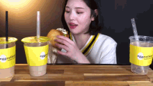 a woman eating a sandwich next to a cup that says eggcellent on it