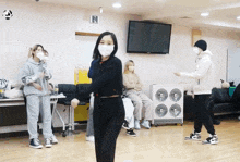 a group of people wearing face masks are dancing in a dance studio