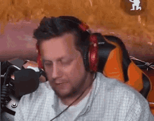 a man wearing headphones is sitting in front of a microphone in a gaming chair .