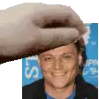 a hand is holding a man 's head in front of a sign that says ' s ' on it