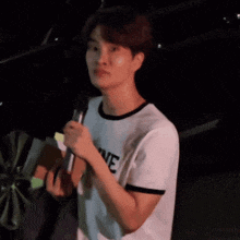 a young man is holding a microphone in his hand and talking into it .